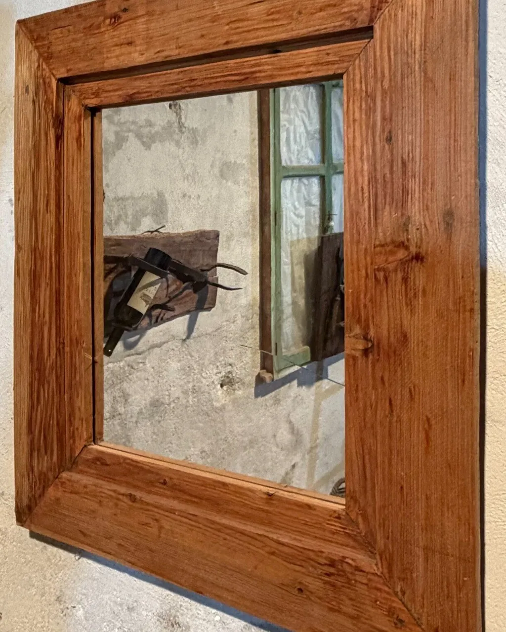 Espejo de marco ancho de madera cálida colgado en una pared encalada
