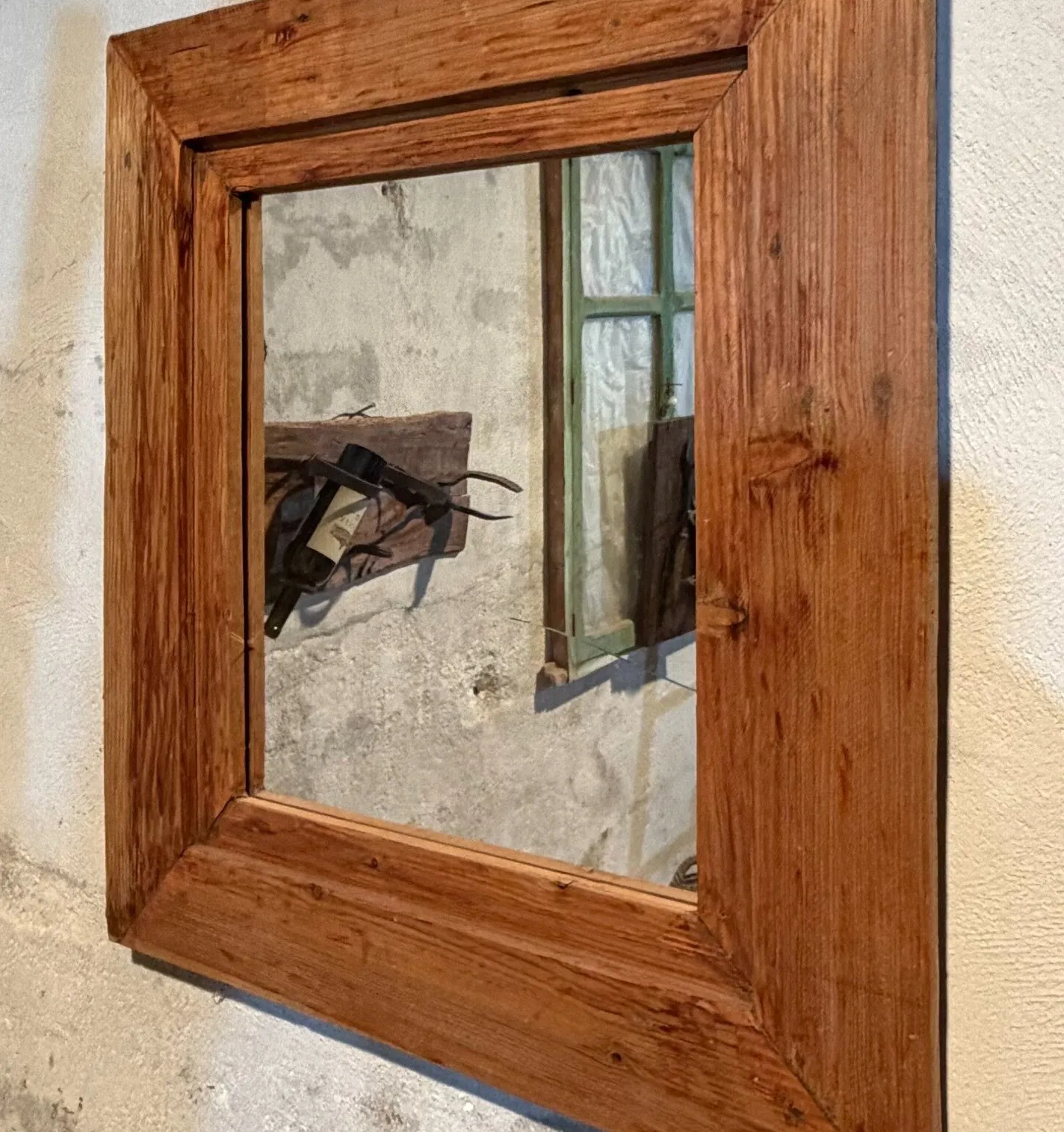 Espejo de marco ancho de madera cálida colgado en una pared encalada