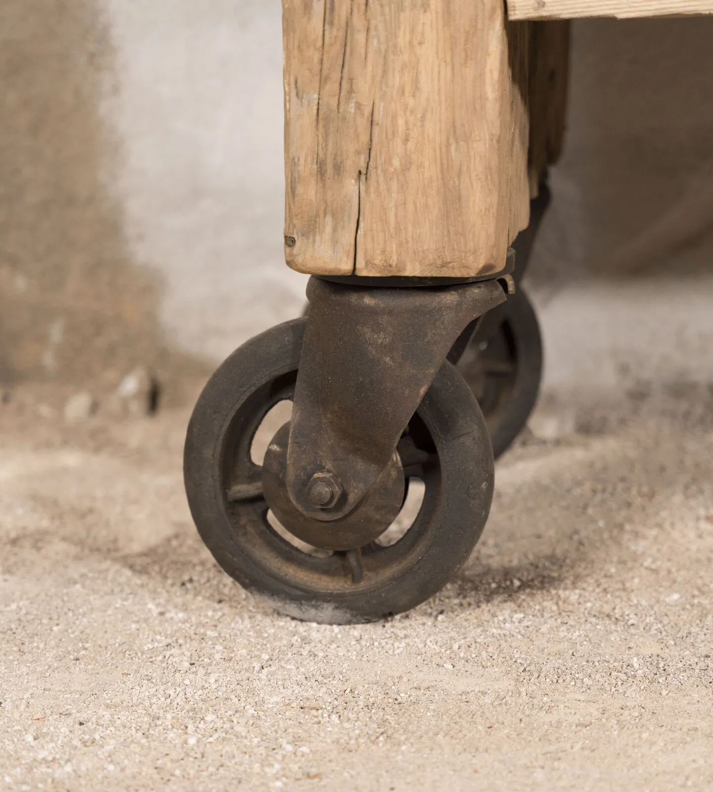 Rueda giratoria de hierro bajo una pata de madera clara