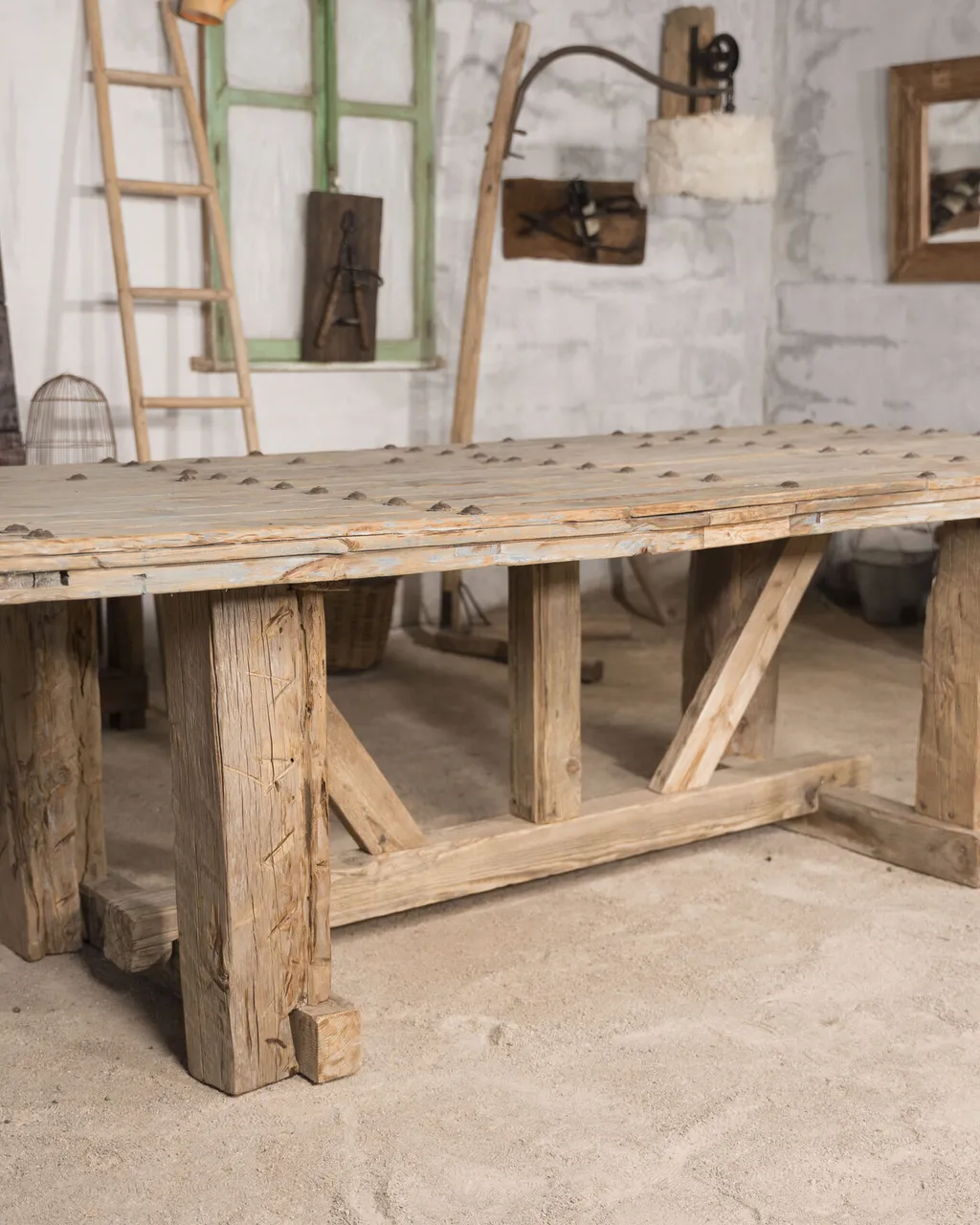 Mesa de comedor de madera recuperada con patas en caballete y tablero claveteado
