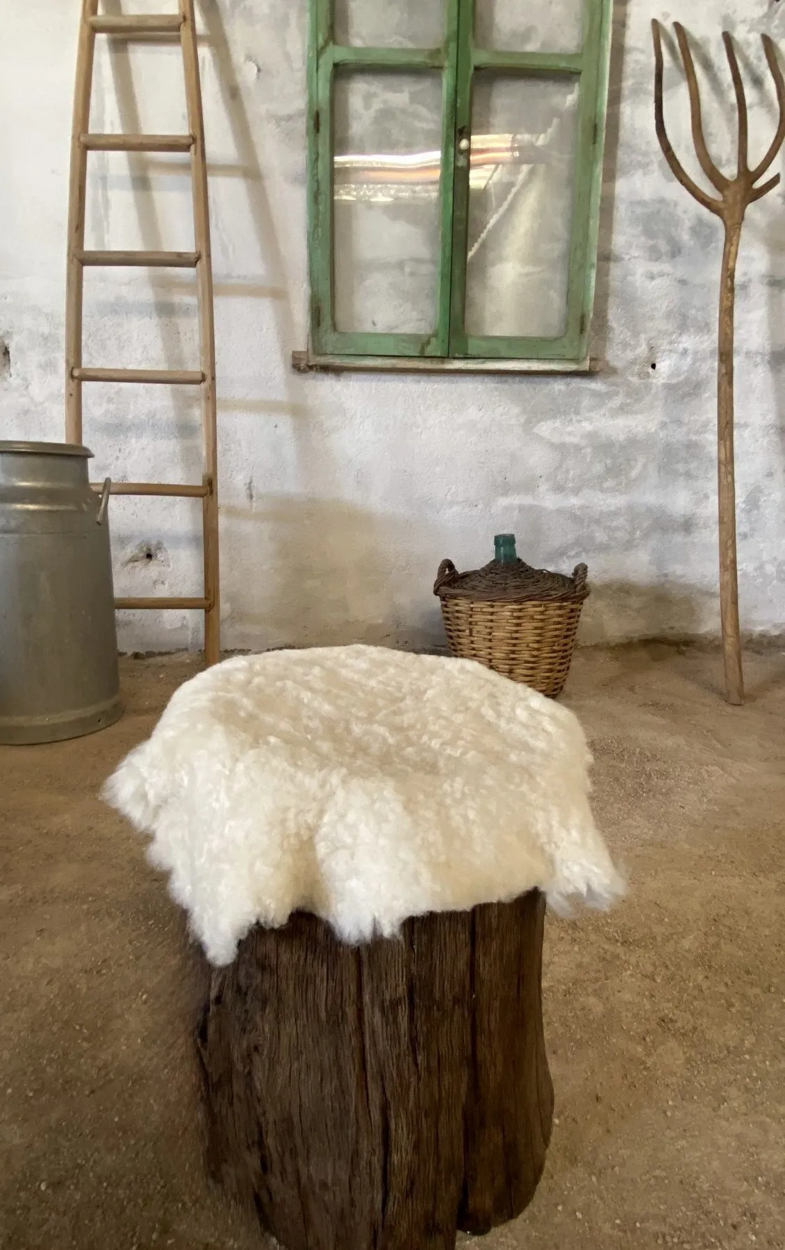 Taburete de tronco oscuro con piel de oveja encima, en el taller